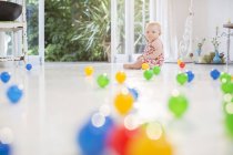 Baby girl with toys on kitchen floor — Stock Photo