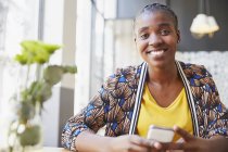 Ritratto donna d'affari sorridente che tiene il telefono delle cellule in caffè — Foto stock