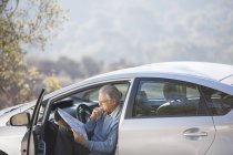 Homme âgé en voiture regardant la carte — Photo de stock