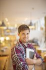 Щасливий молодий чоловік тримає книги в кафе — стокове фото