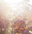 Portrait smiling boy holding bunch of autumn leaves — Stock Photo