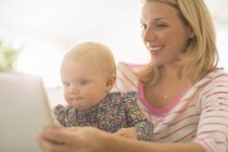 Madre y niña usando tableta digital - foto de stock