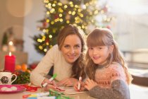 Retrato sonriente madre e hija para colorear con marcadores en la sala de estar de Navidad - foto de stock