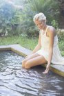 Mujer colgando las piernas en la piscina - foto de stock