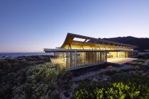 Iluminada moderna casa de luxo vitrine exterior com vista para o mar ao entardecer — Fotografia de Stock