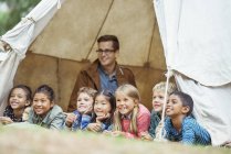Students and teacher smiling in tent at campsite — Stock Photo