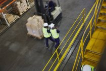 Forklift and workers on the move in distribution warehouse — Stock Photo