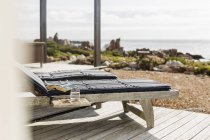 Buch und Wasser im Liegestuhl auf der Terrasse mit Blick auf das Meer — Stockfoto