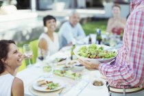 Man serving friends at table outdoors — Stock Photo
