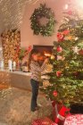Девушка висит снежинка украшение на елке в гостиной — стоковое фото