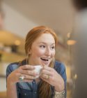 Щаслива молода жінка п'є каву в кафе — стокове фото