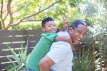 Portrait of happy grandfather piggybacking grandson — Stock Photo