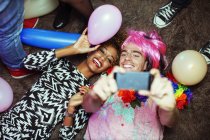 Пара, делающая селфи со смартфоном на полу на вечеринке — стоковое фото