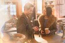 Couple with cell phone and coffee at counter in cafe — Stock Photo