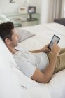 Человек с помощью цифрового планшета на кровати — стоковое фото