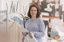 Retrato sonriente comprador de moda en estante de ropa - foto de stock