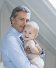 Father holding baby indoors — Stock Photo