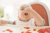 Baby boy eating in high chair — Stock Photo