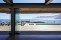 Moderna casa de luxo vitrine pátio com vista para a piscina e vista para o mar ensolarado — Fotografia de Stock