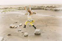 Exuberant girl jumping for joy on beach rocks — Stock Photo