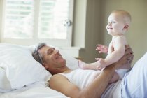 Father playing with baby on bed — Stock Photo
