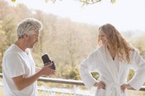 Man with old-fashioned camera photographing woman in bathrobe on autumn balcony — Stock Photo