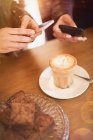 Women with camera phones photographing cappuccino design at cafe table — Stock Photo