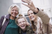 Laughing mother and daughters taking selfie — Stock Photo