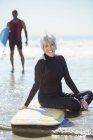 Portrait of senior woman on surfboard at beach — Stock Photo