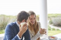 Laughing couple drinking coffee on patio — Stock Photo