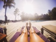 Mulher tomando banho de sol na ensolarada piscina tropical — Fotografia de Stock