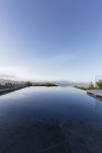 Tranquil luxury infinity pool below blue sky — Stock Photo