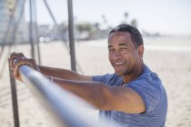 Portrait of senior man leaning on bar at beach playground — Stock Photo