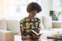 Donna d'affari che legge un libro sul divano a casa — Foto stock