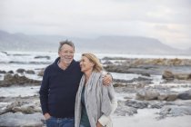 Sorridente coppia anziana a piedi sulla spiaggia invernale — Foto stock