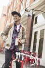 Чоловік п'є каву на велосипеді на міській вулиці — стокове фото