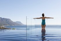 Mulher desfrutando de piscina infinita com vista para o oceano — Fotografia de Stock