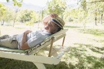 Homem mais velho relaxante na cadeira de gramado ao ar livre — Fotografia de Stock