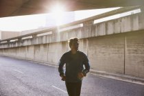 Male runner running into urban tunnel — Stock Photo