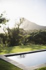 Sun shining over mountain and luxury lap pool — Stock Photo