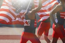 Легка атлетика спортсменів тримається треку американськими прапорами — стокове фото