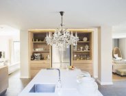 Chandelier hanging over luxury kitchen island — Stock Photo