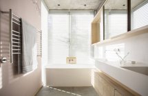Luce splendente attraverso tende dietro la vasca da bagno nel bagno di lusso — Foto stock