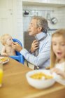 Pai e crianças tomando café da manhã na cozinha — Fotografia de Stock
