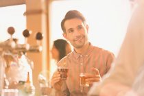 Улыбающийся кавказский мужчина пробует пиво в баре — стоковое фото