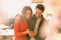 Casal afetuoso usando telefone celular no café — Fotografia de Stock