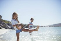 Menina salpicando na água na praia — Fotografia de Stock