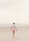 Teenage girl walking in sand on overcast summer beach — Stock Photo