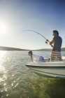 Батько і син рибалять на човні — стокове фото