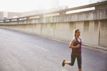 Жінка біжить на сонячній міській вулиці — стокове фото